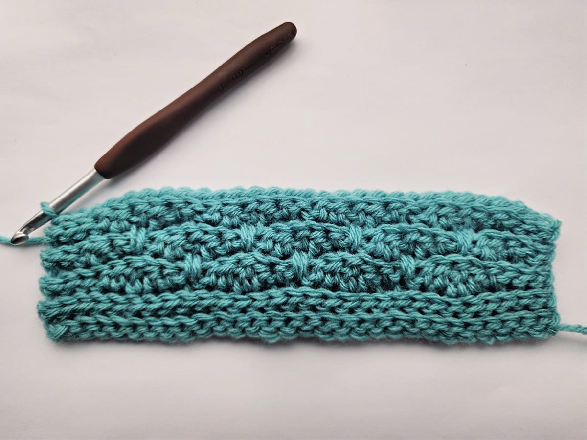 Ten rows of a knit-look crochet blanket swatch complete.