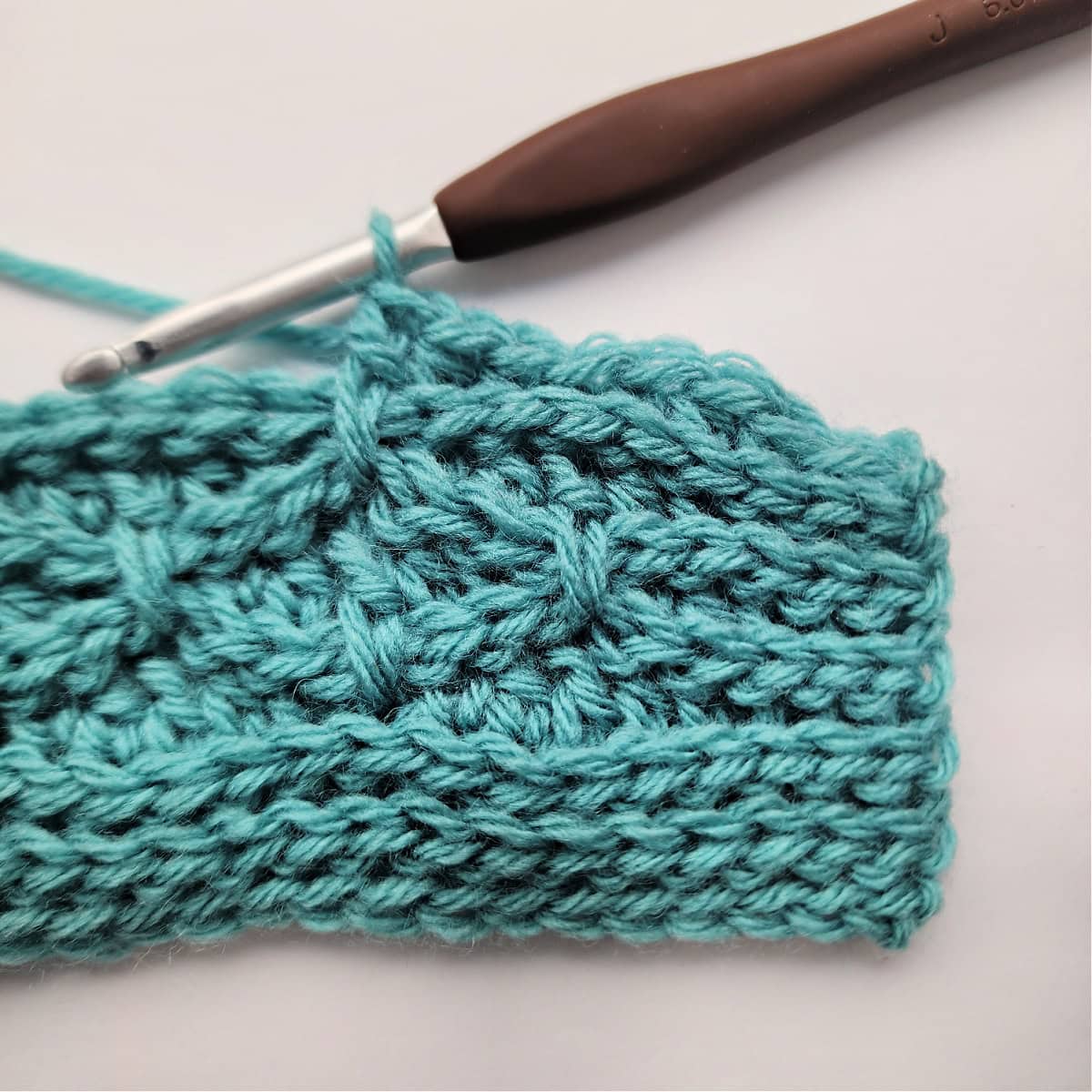 A close-up of a double crochet stitch worked into a double crochet stitch two rows down in row 11.
