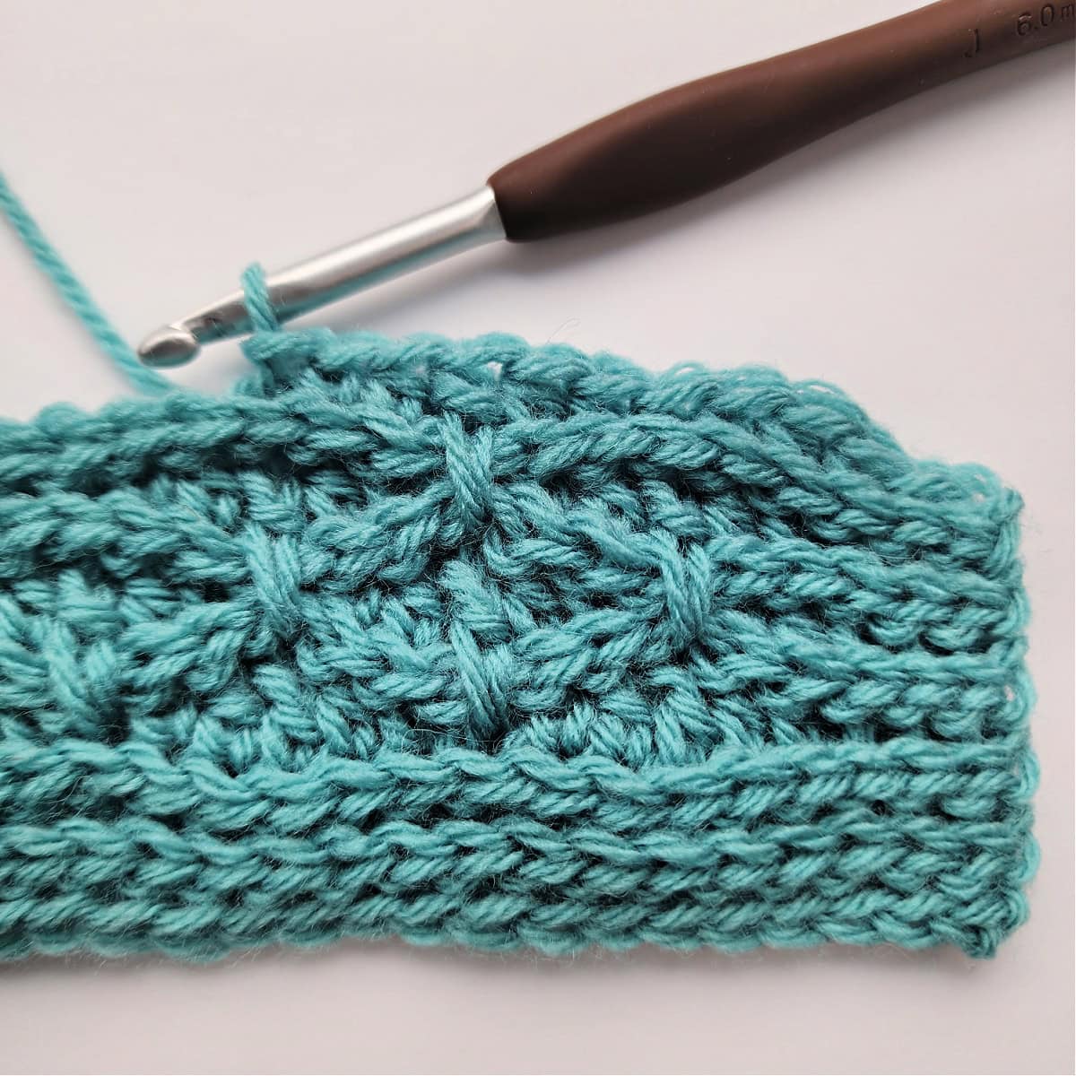The beginning of a knit-look stitch pattern repeat being worked in row 11.