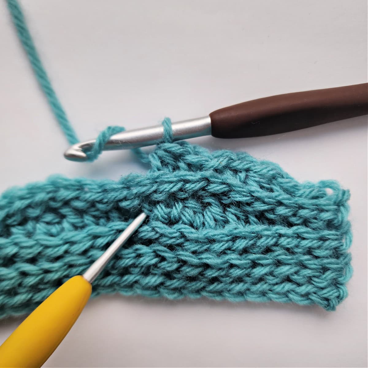 A small knit-look crochet swatch and a crochet hook.