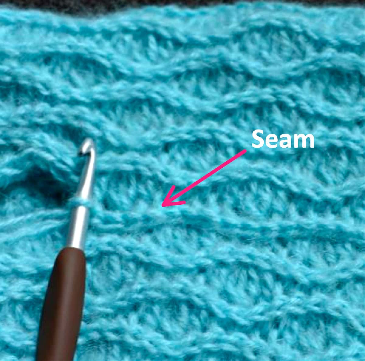 A crochet hook inserted into a stitch of a crochet project.