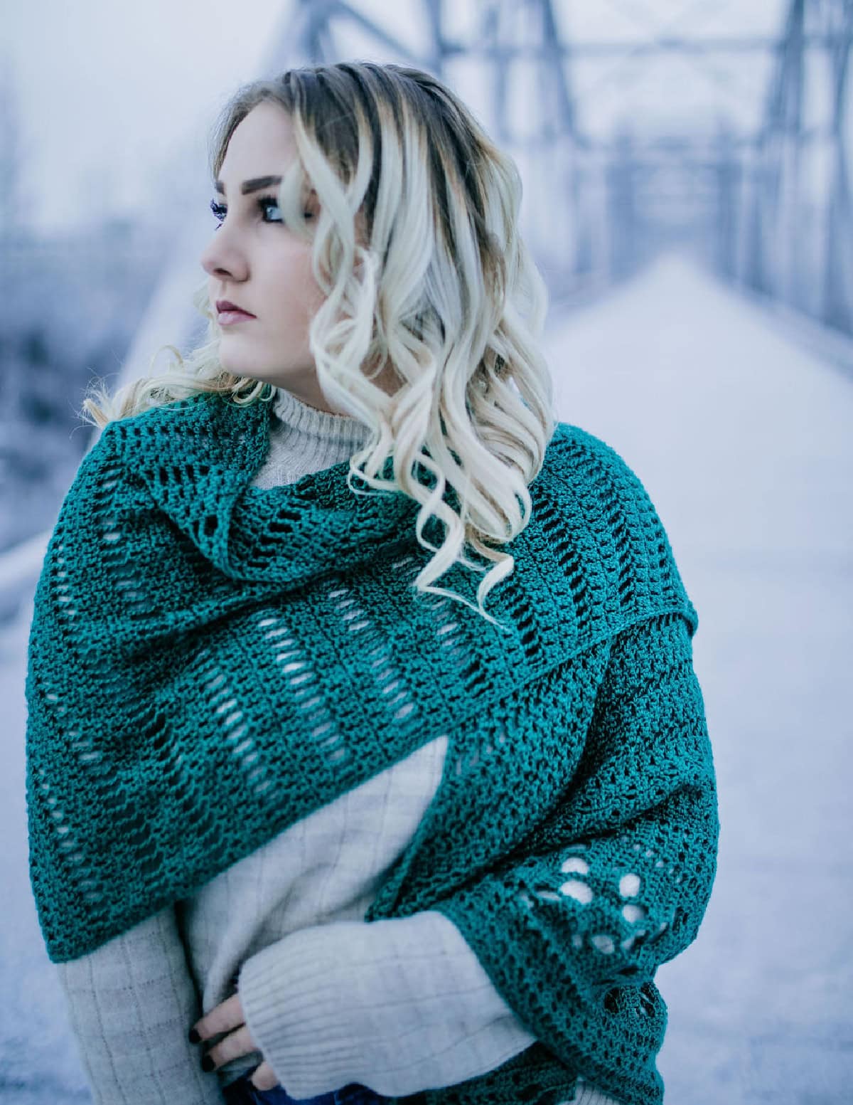 Woman with a green crochet shawl draped around her shoulders and arm.