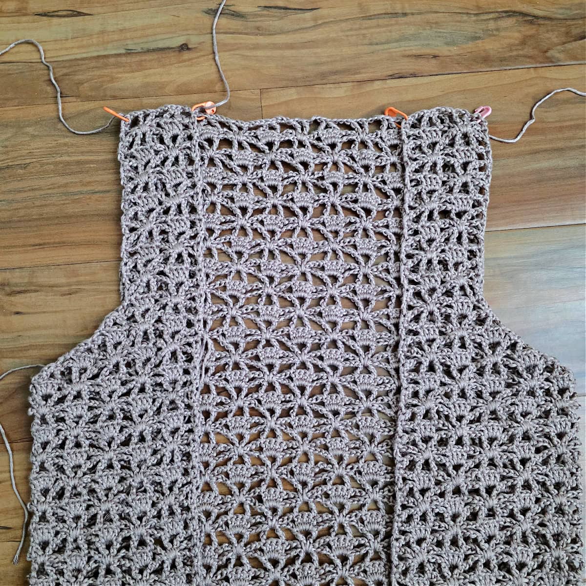 A close-up of the front panels held to the back panel with stitch markers before seaming.