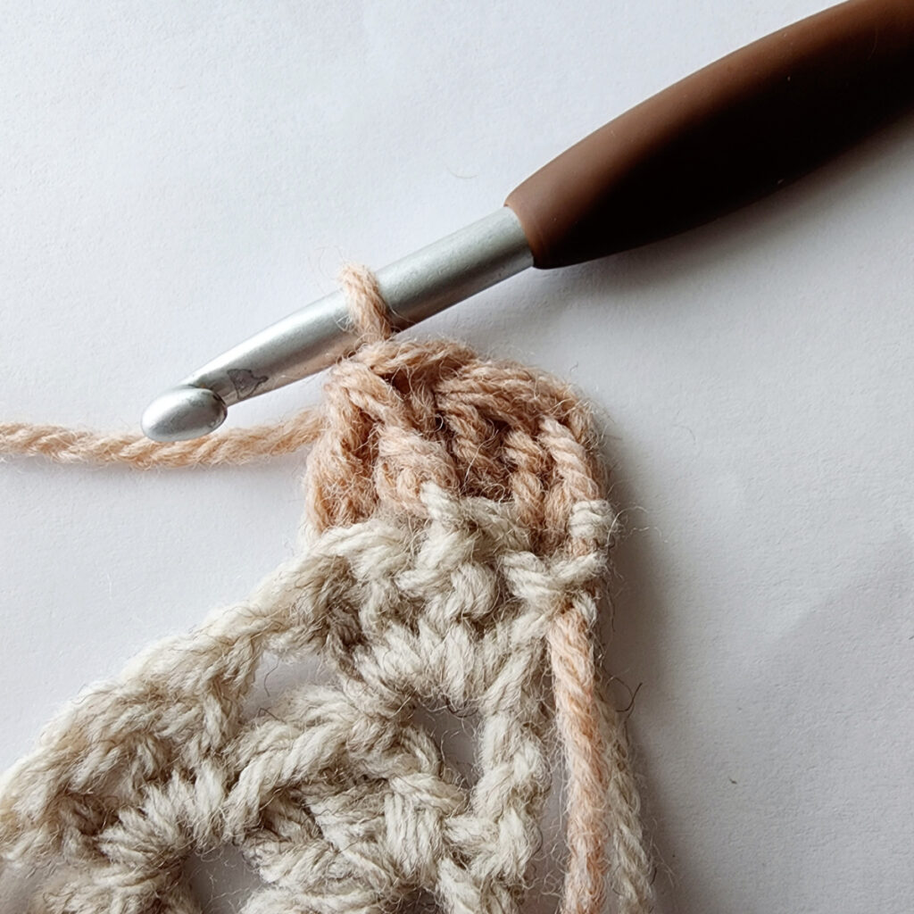 Decreasing to create the corner of a granny square motif with a crochet hook.