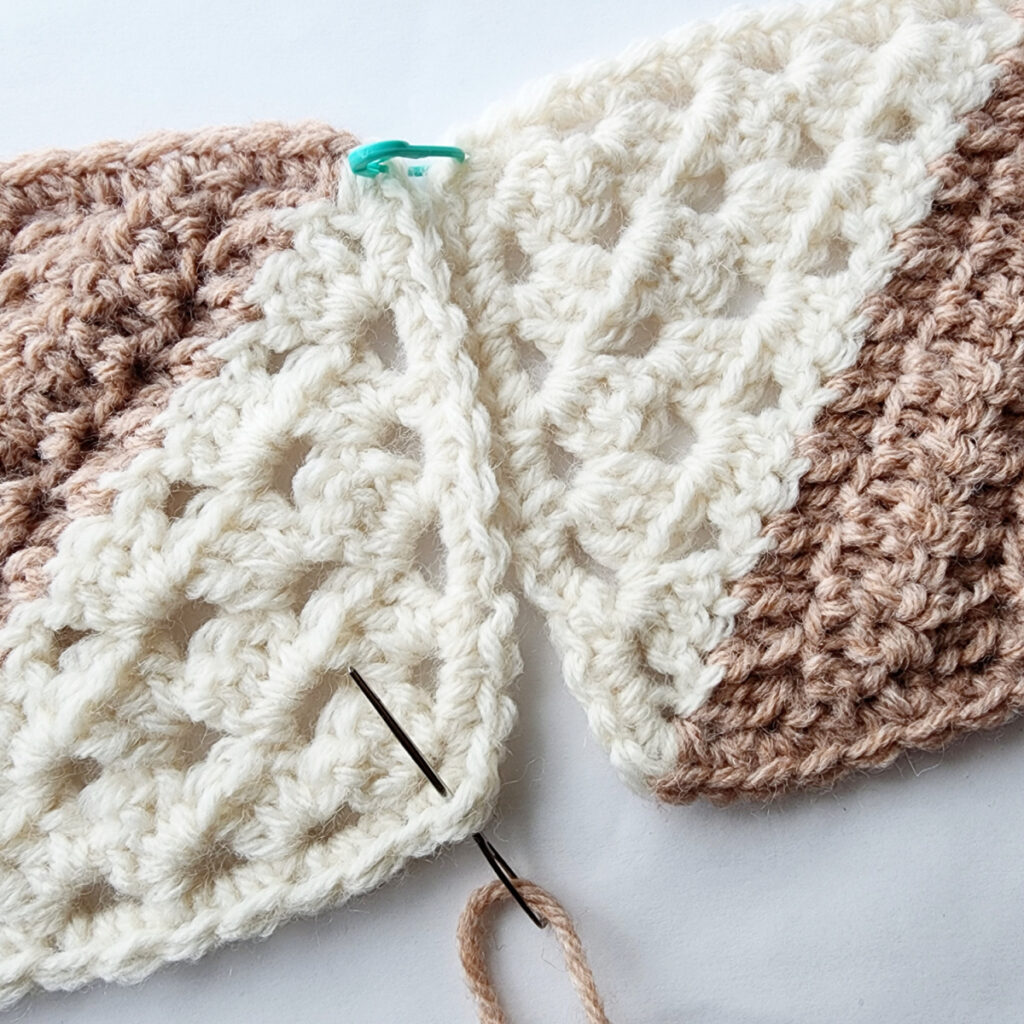 Seaming two crochet granny square motifs with a needle.