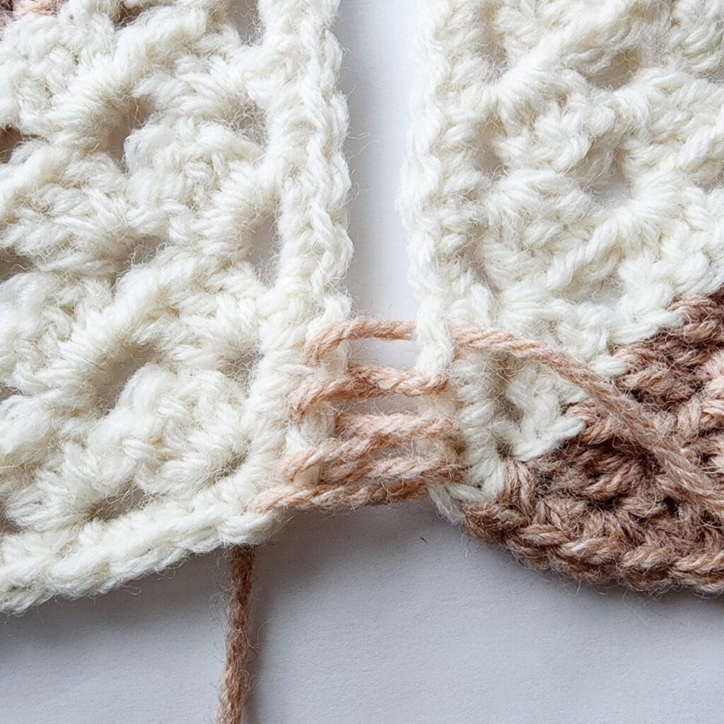 Seaming two crochet granny square motifs.