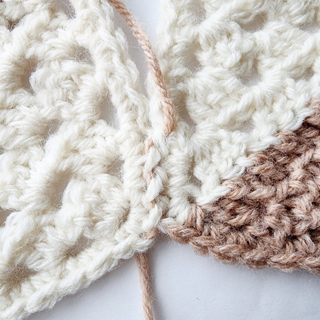 Seaming two crochet granny square motifs.