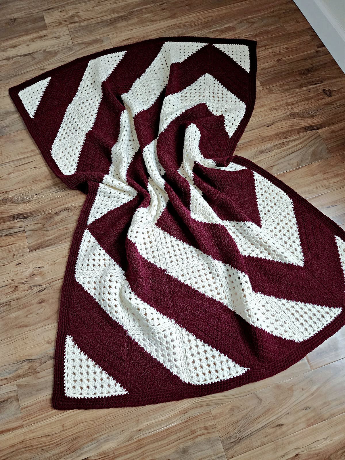 Granny squares crochet blanket laying over the wooden floor scrunched up in the middle.