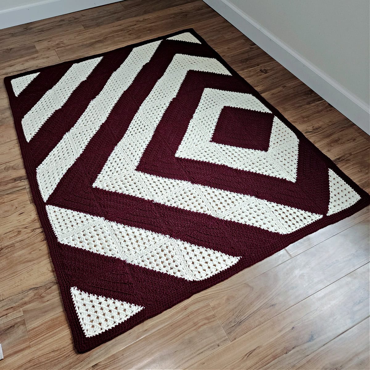 Granny squares crochet blanket spread over the wooden floor.