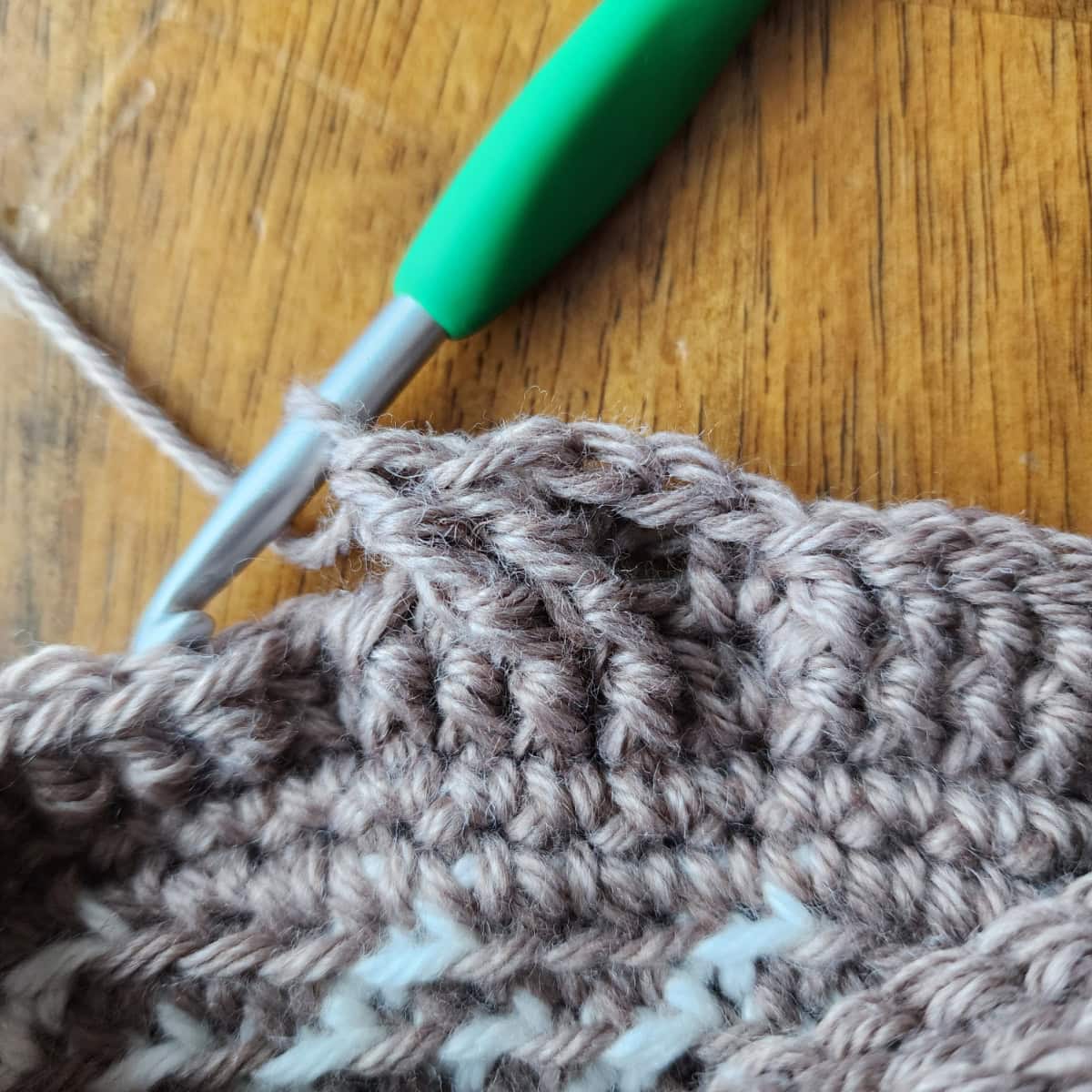 Working the 4-strand cable twists of the decorative cuff of the crochet slipper boot.
