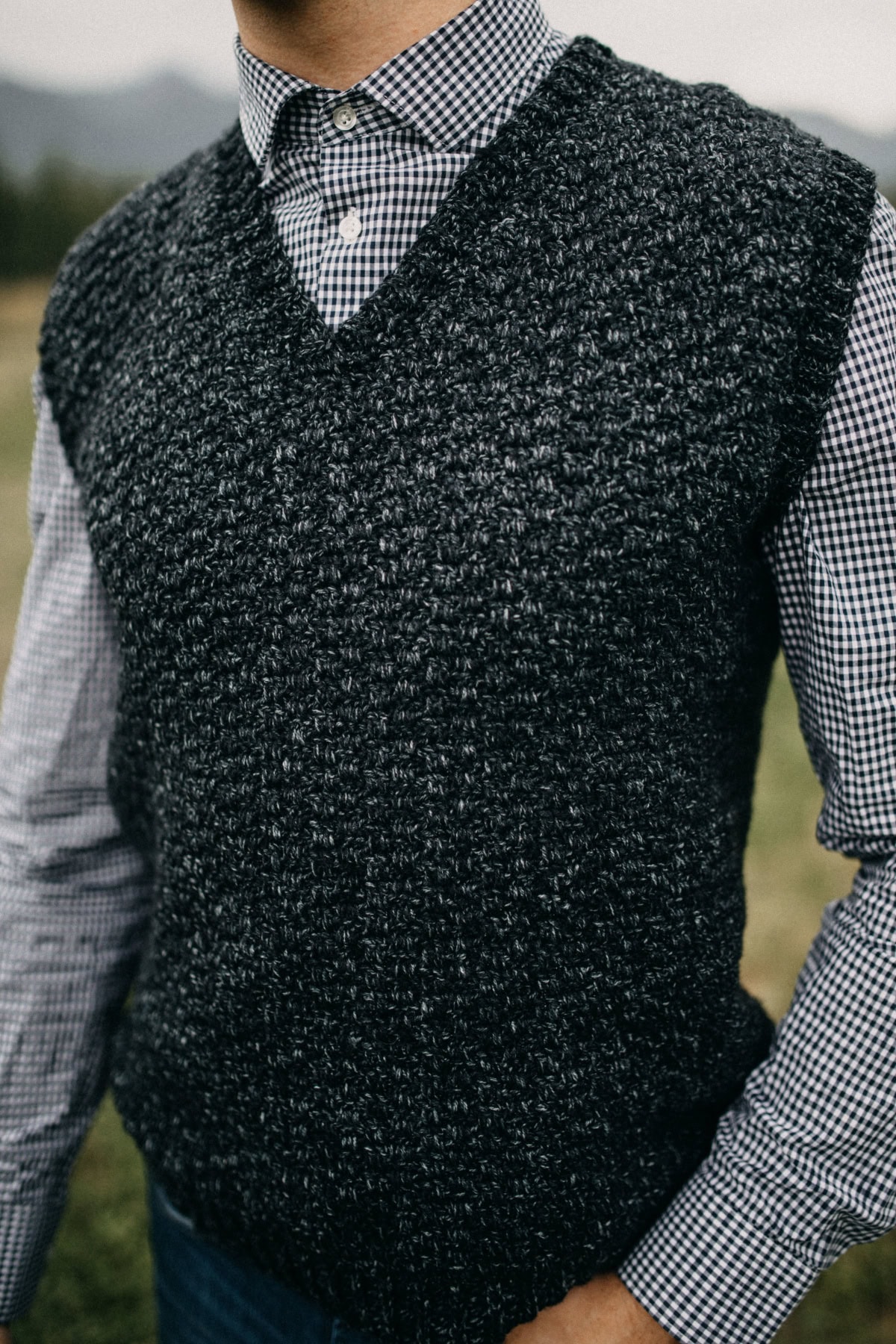 A dark crochet vest and gray button-down shirt.