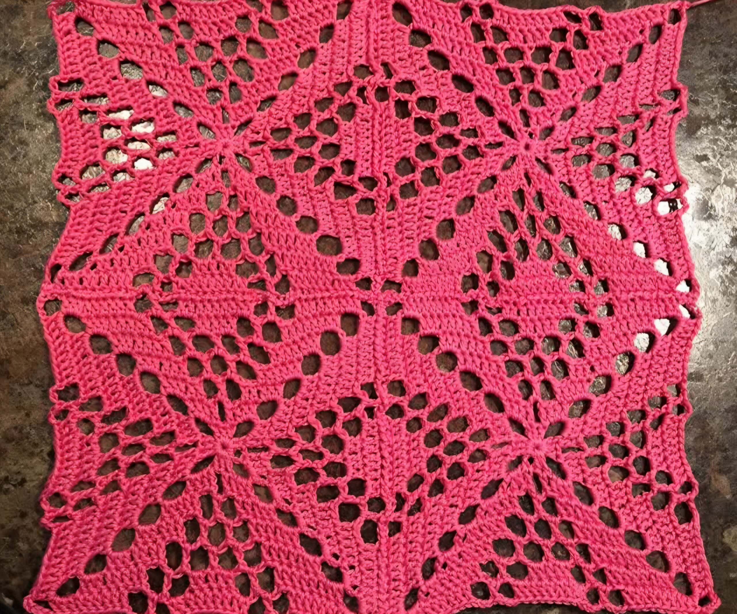 Four bright pink crochet squares seamed together.