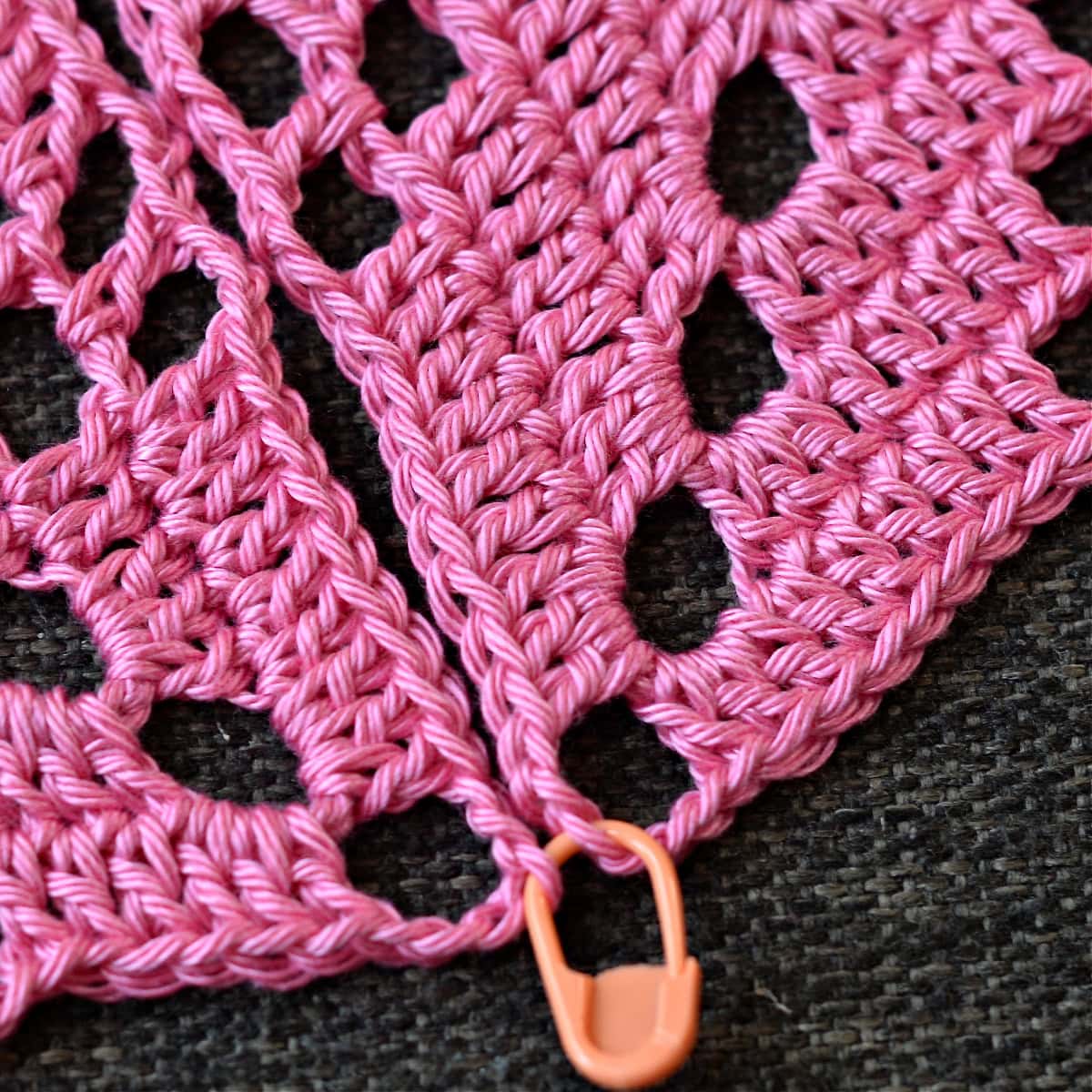 Using a stitch marker to hold two granny squares together.