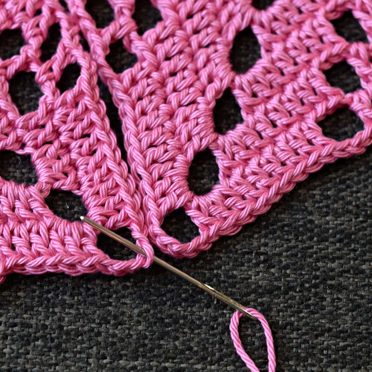 Needle inserted in one corner of the granny square.