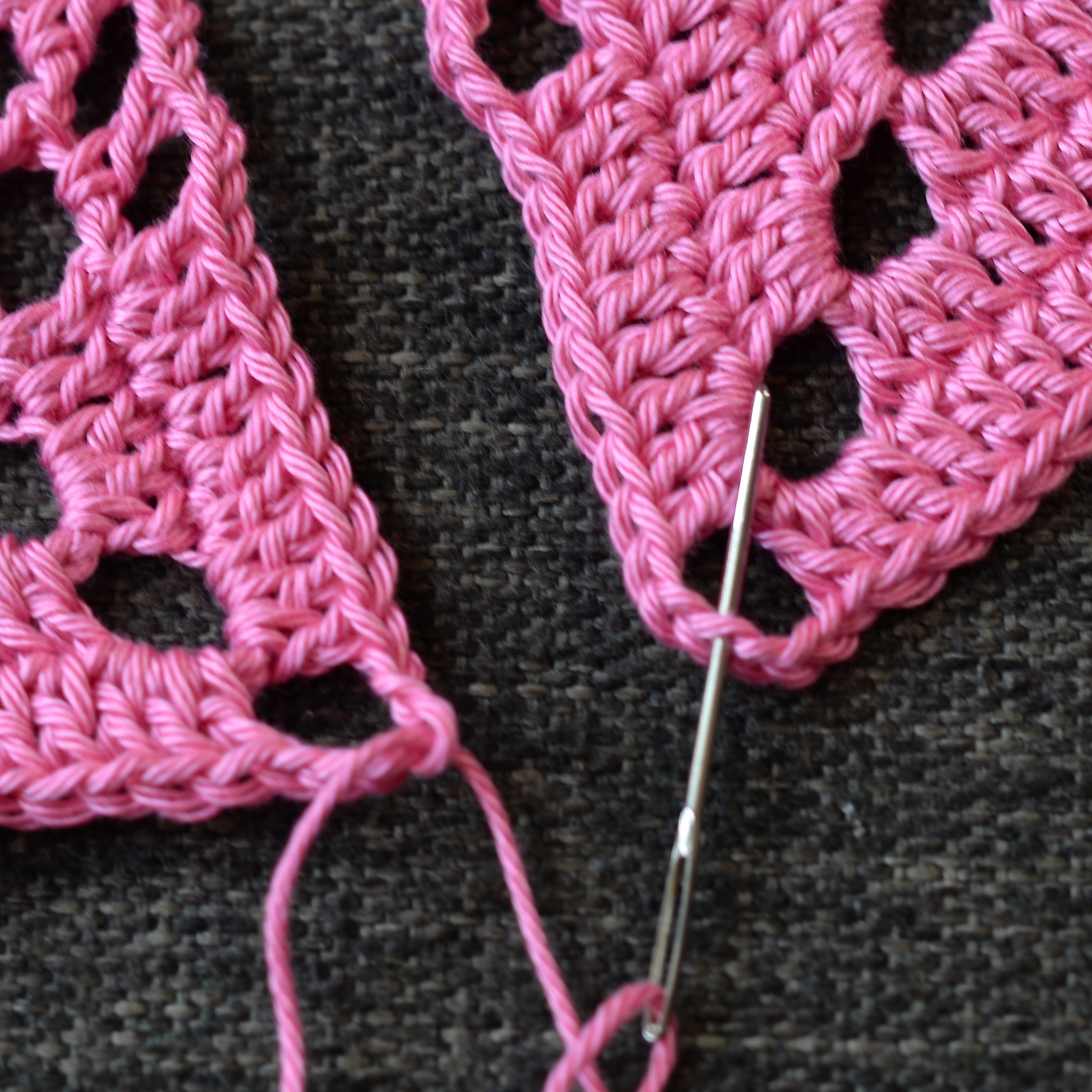 Needle inserted in one corner of the granny square.