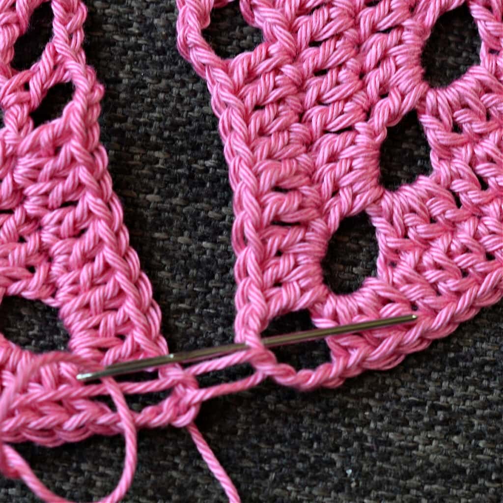 Using a needle to seam the granny squares together.