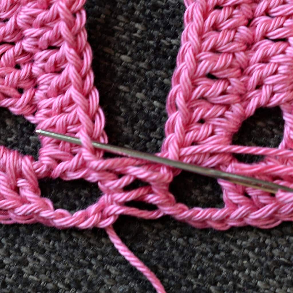 Using a needle to seam the granny squares together.