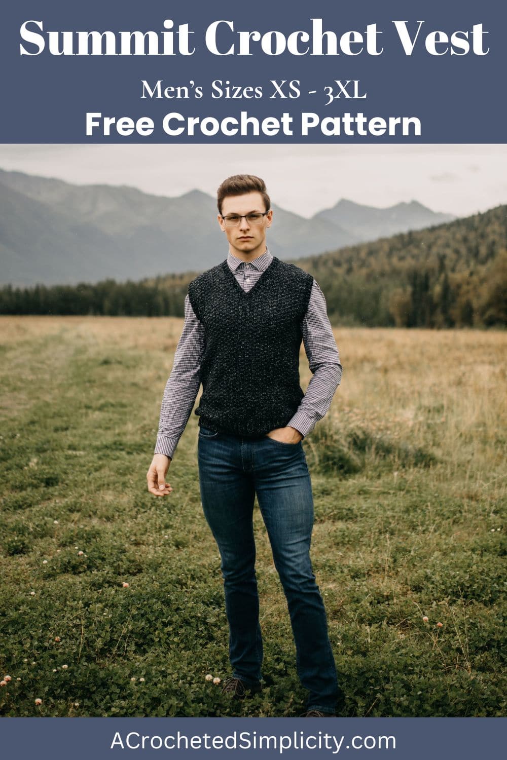 Man standing in a field wearing a dark crochet vest and glasses with one hand in his pocket.