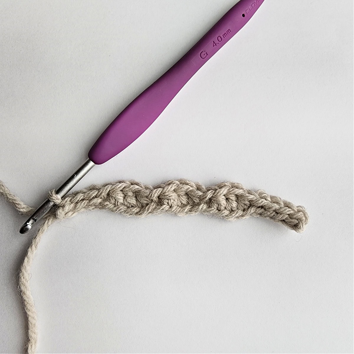 Row 1 of the crochet ornament with a purple crochet hook.