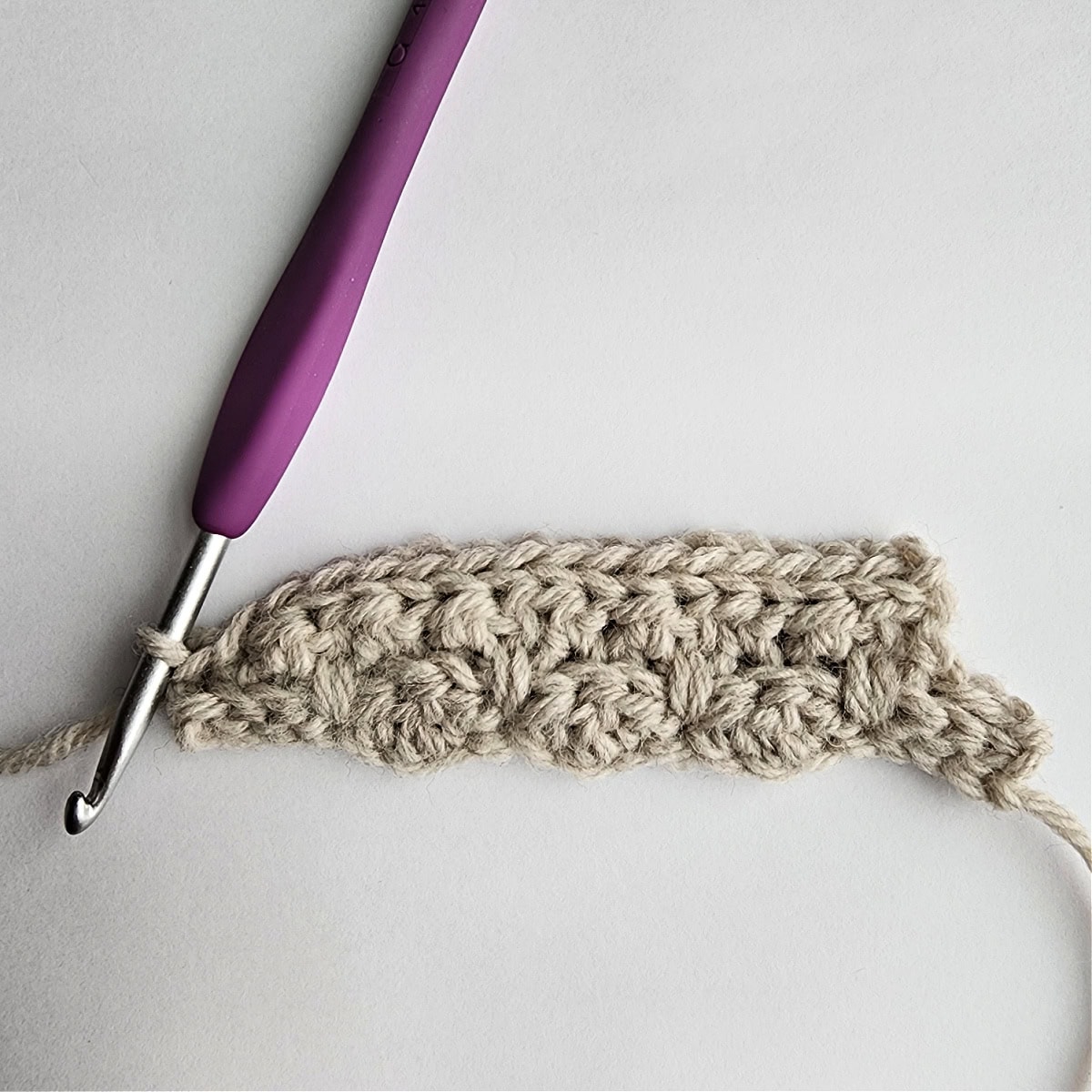 Row 4 of the crochet ornament with a purple crochet hook.