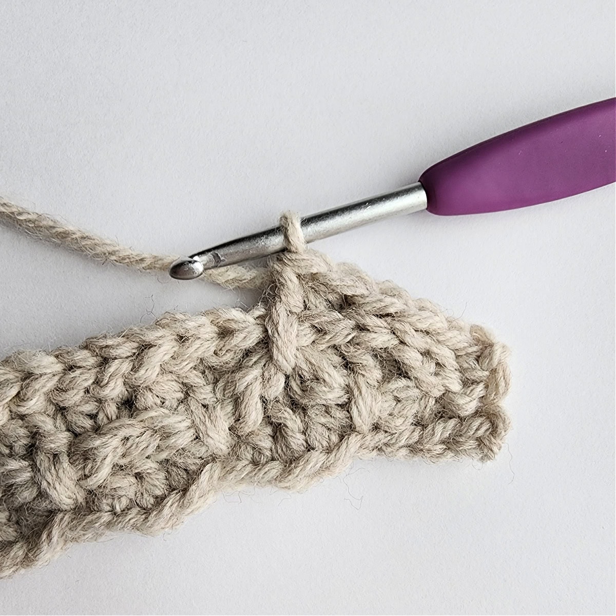 Row 5 of the crochet ornament with a purple crochet hook.