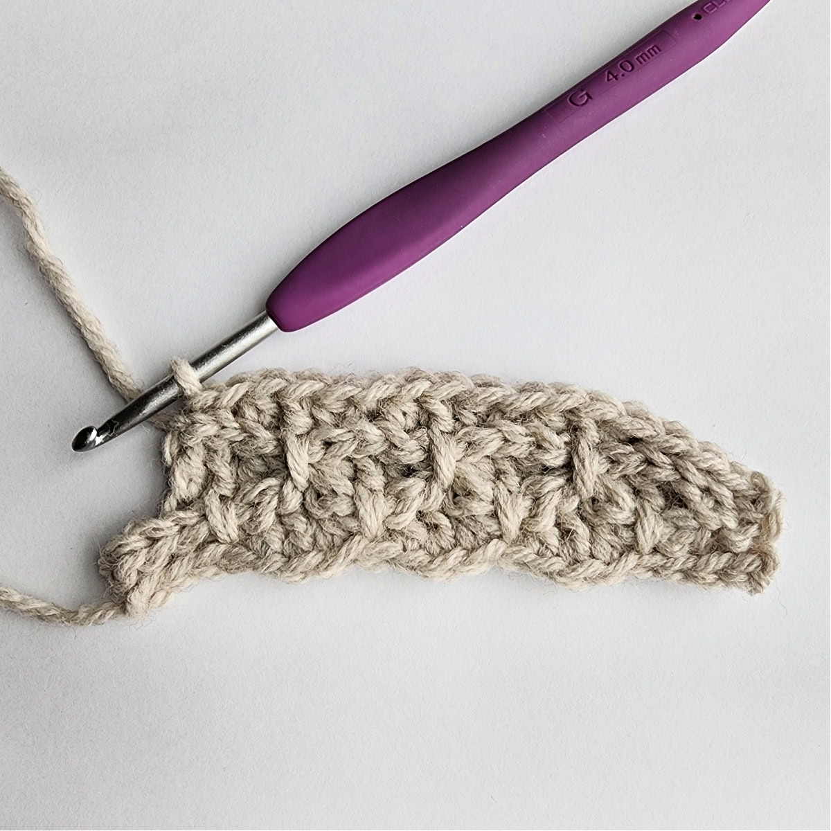 Row 5 of the crochet ornament with a purple crochet hook.