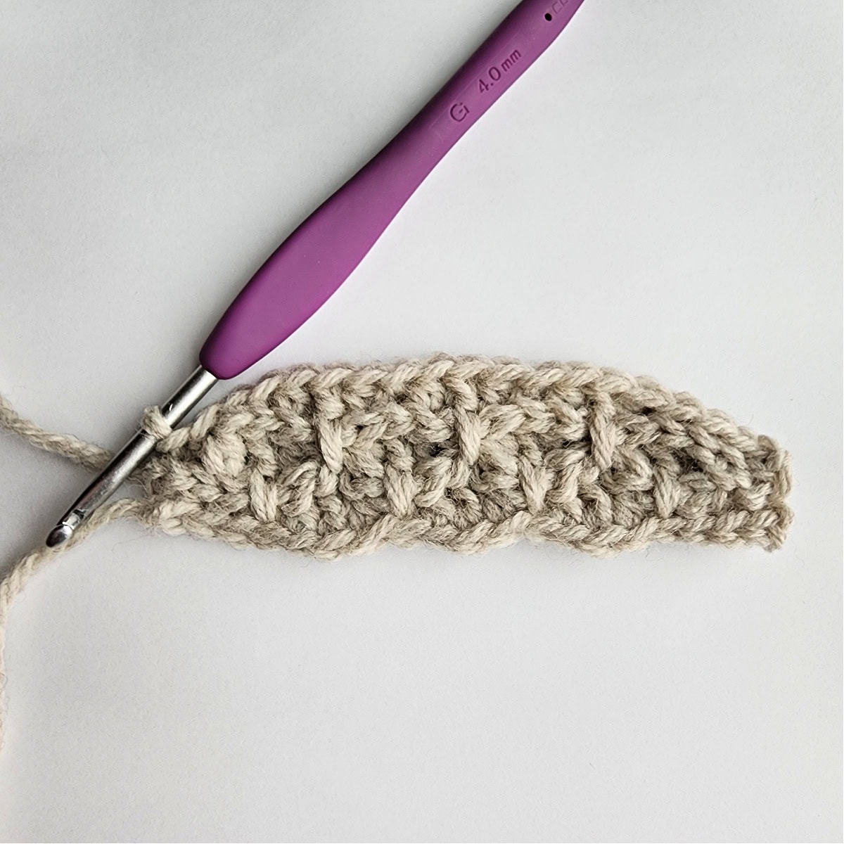 Row 5 of the crochet ornament with a purple crochet hook.