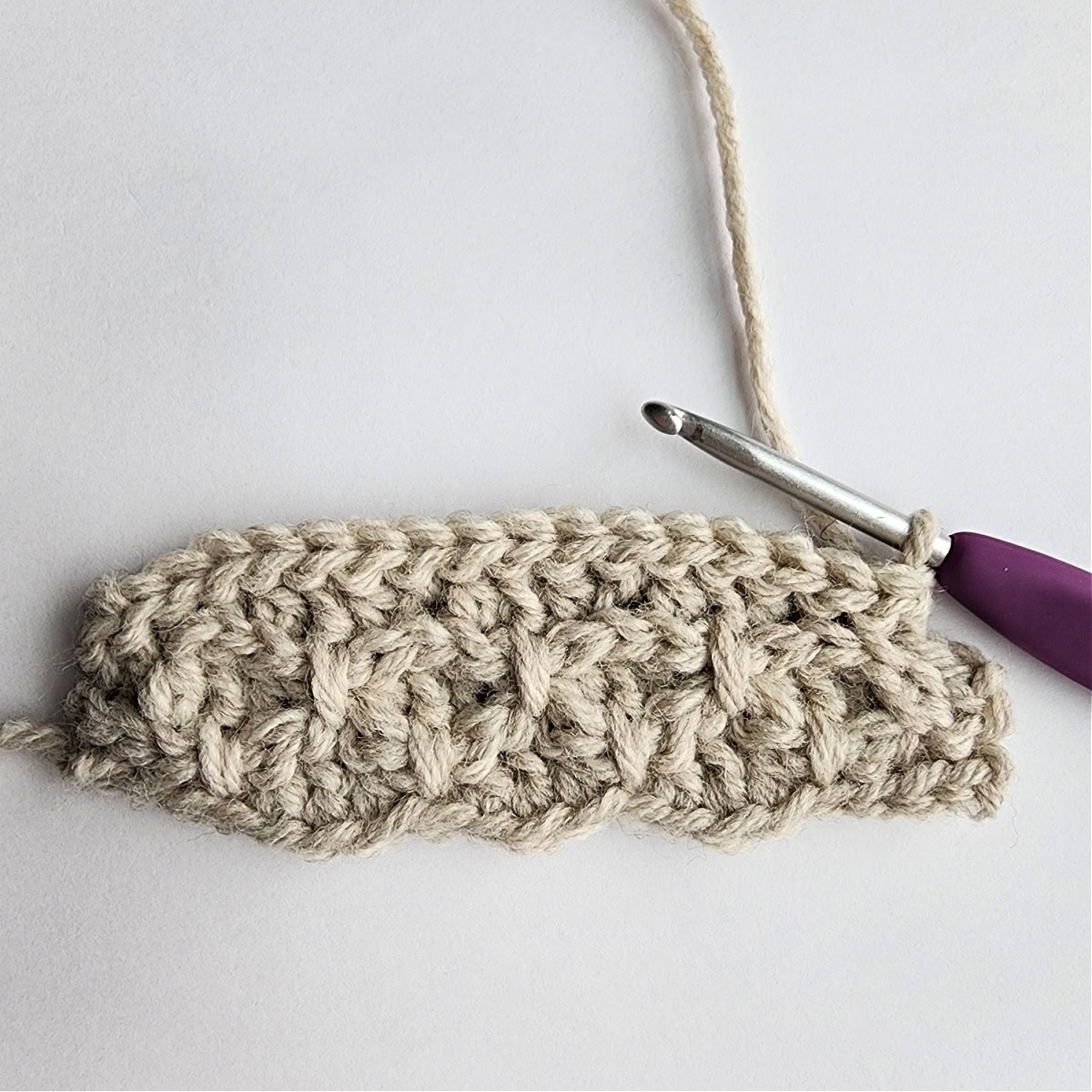 Starting row 7 of the crochet ornament with a purple crochet hook.