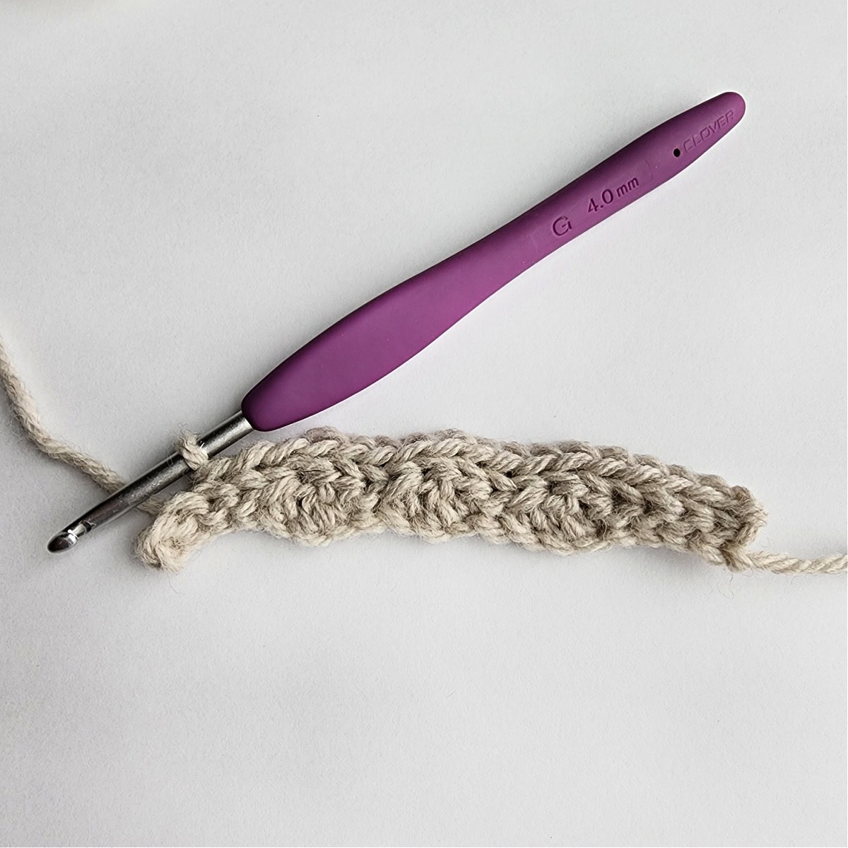 Row 2 of the crochet ornament with a purple crochet hook.