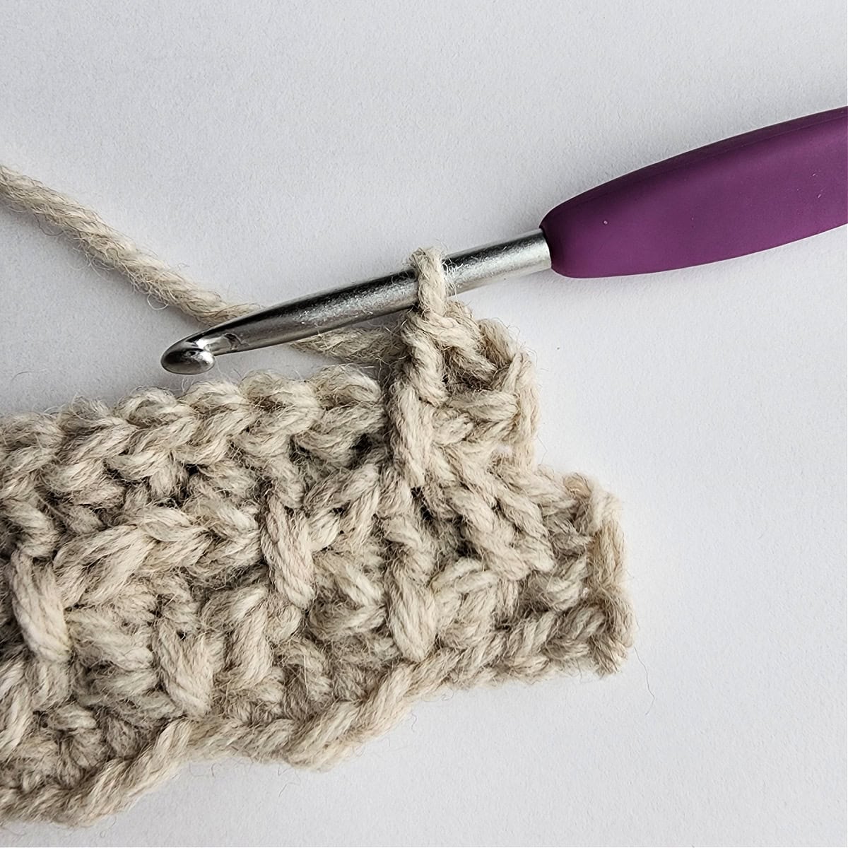 Row 7 of the crochet ornament with a purple crochet hook.
