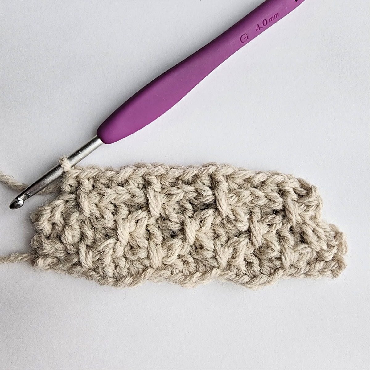 Row 7 of the crochet ornament with a purple crochet hook.