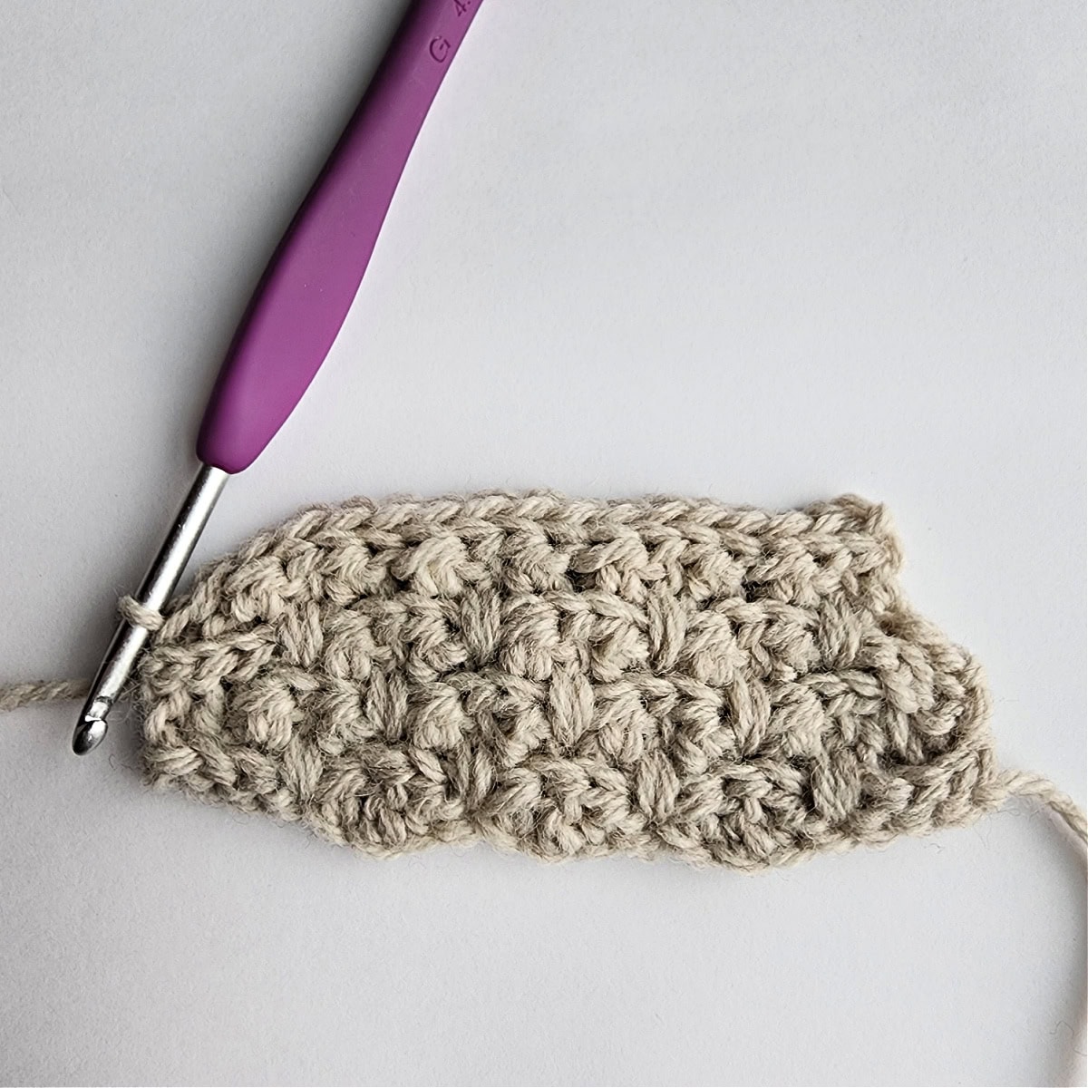 Row 8 of the crochet ornament with a purple crochet hook.