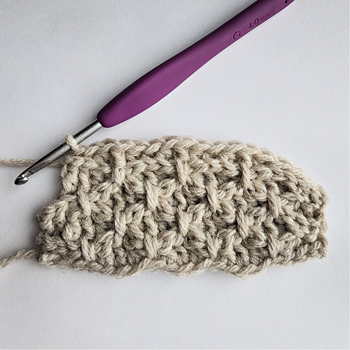 Row 9 of the crochet ornament with a purple crochet hook.