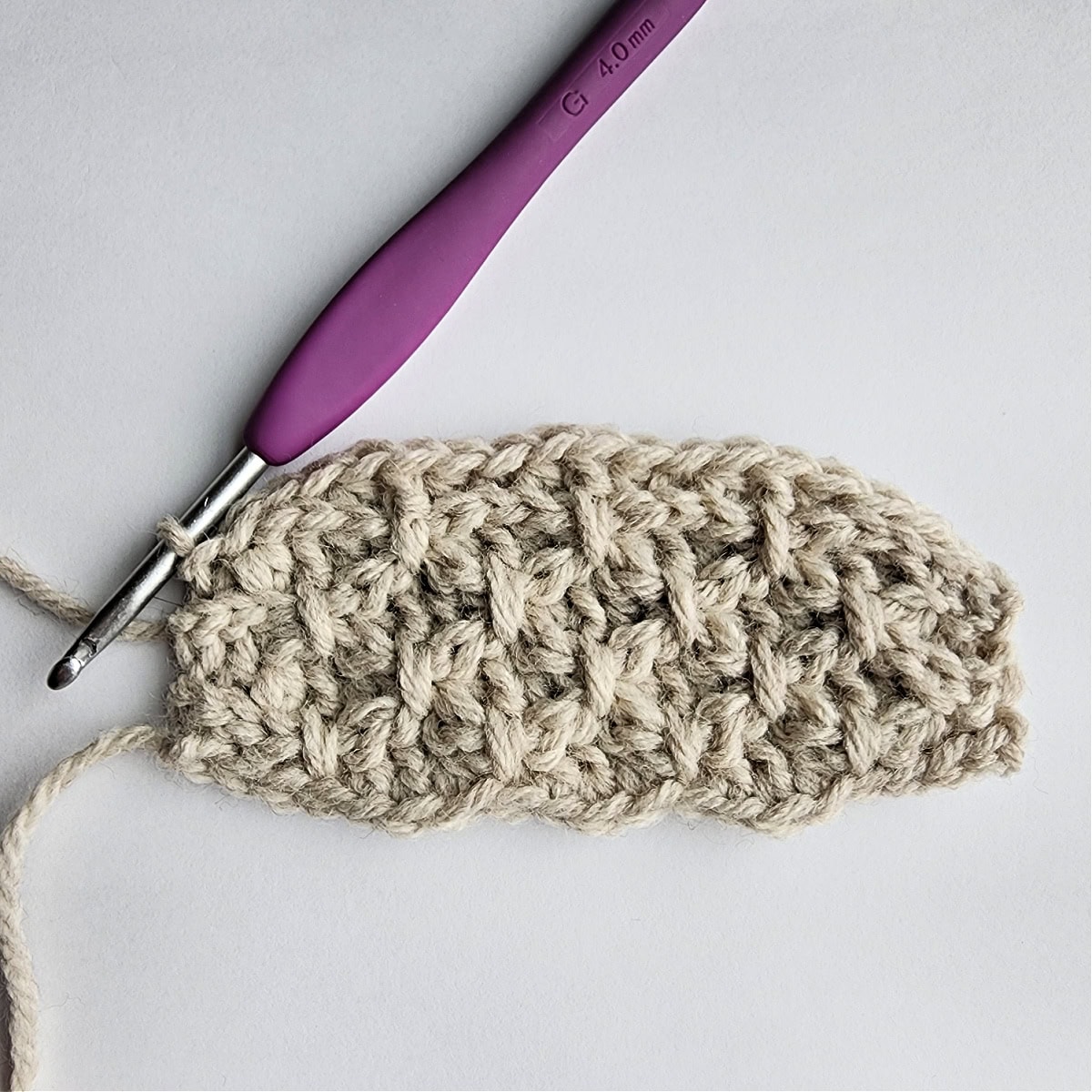 Row 9 of the crochet ornament with a purple crochet hook.