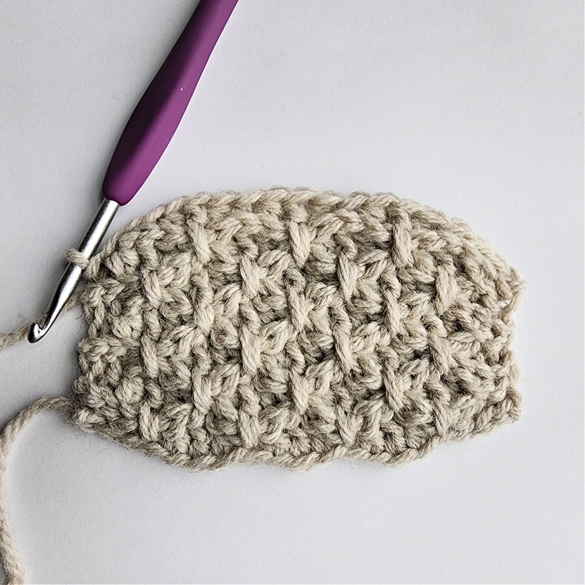 Row 13 of the crochet ornament with a purple crochet hook.