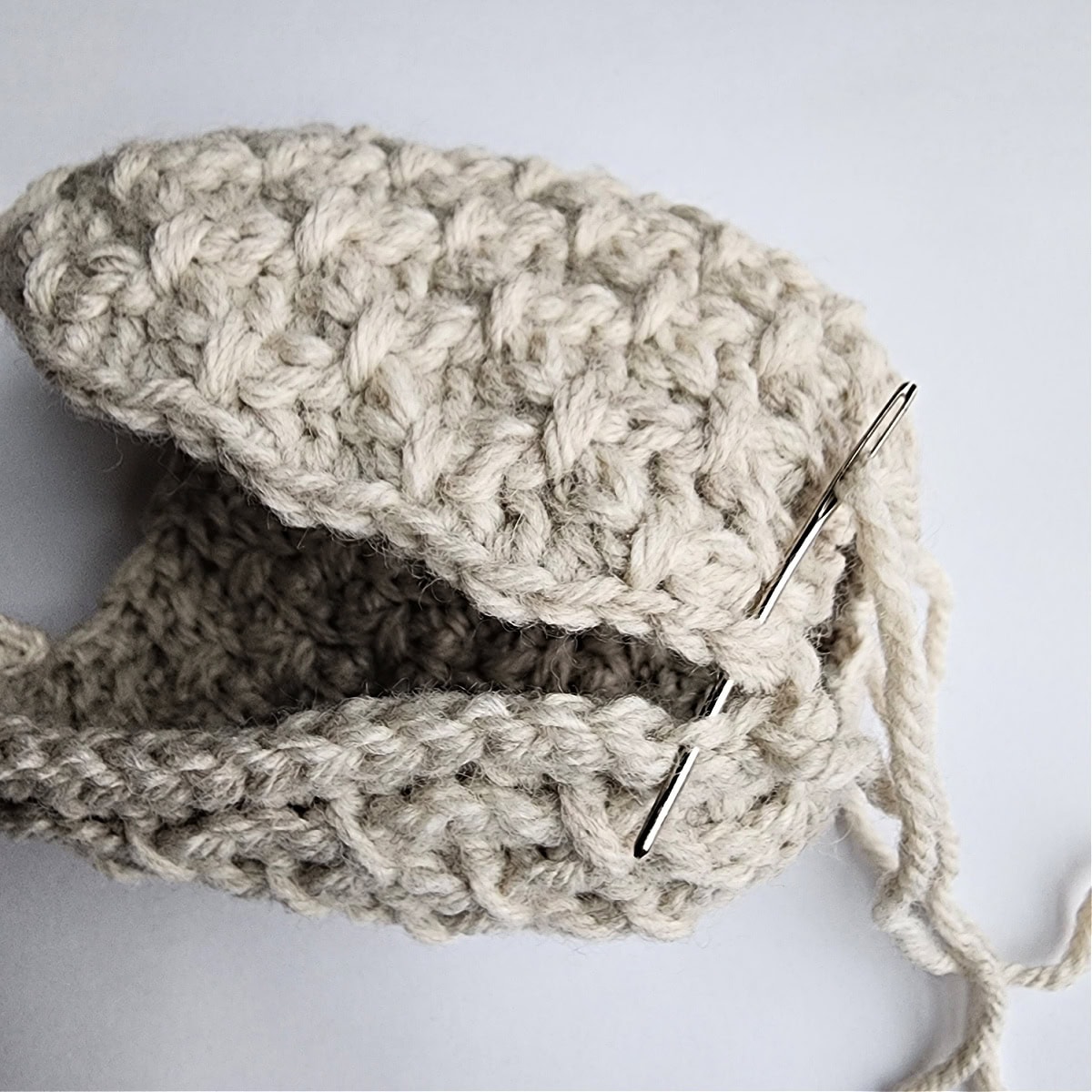 Thread and needle being used to seam the crochet ornament together.