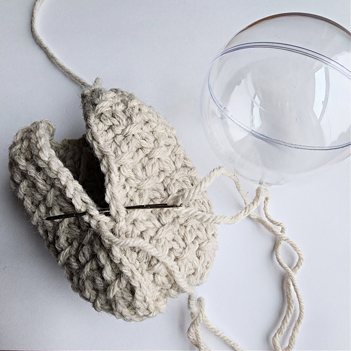 Thread and needle being used to seam the crochet ornament together.