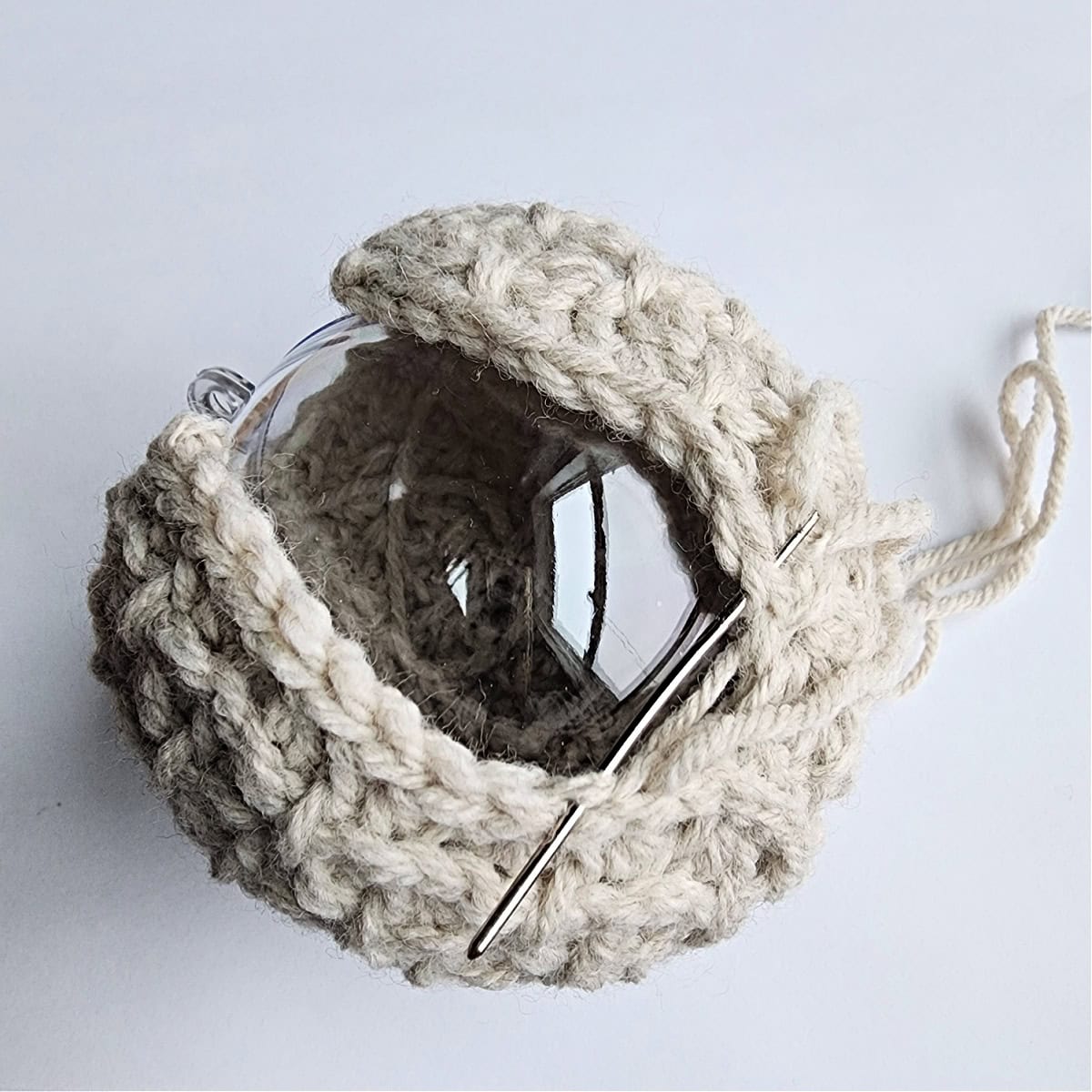 Thread and needle being used to seam the crochet ornament together.