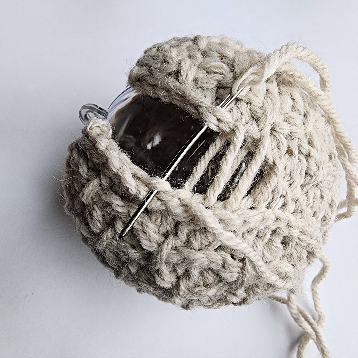 Thread and needle being used to seam the crochet ornament together.