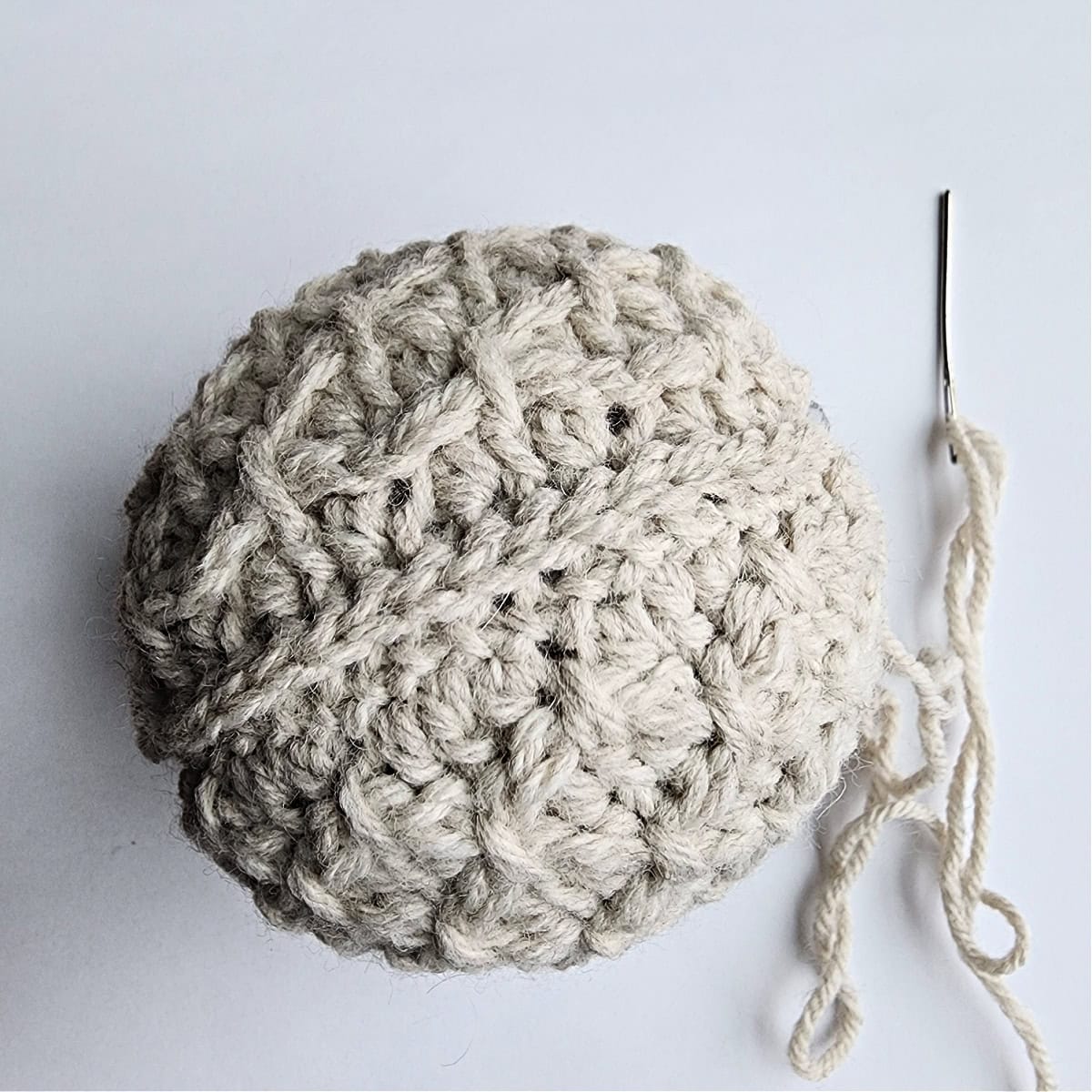 A crochet ornament next to a needle and thread.