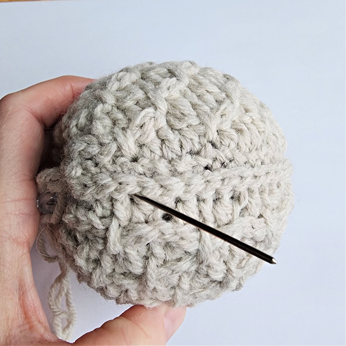 Thread and needle being used to seam the crochet ornament together.