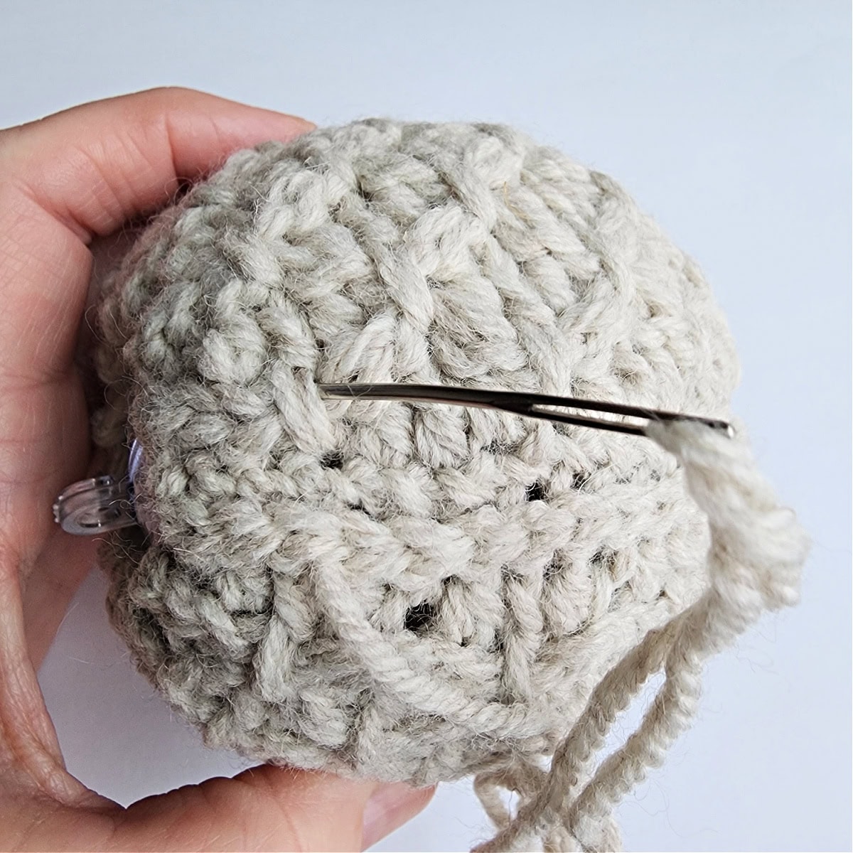 Thread and needle being used to seam the crochet ornament together.