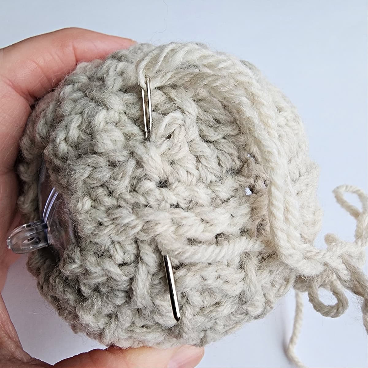 Thread and needle being used to seam the crochet ornament together.