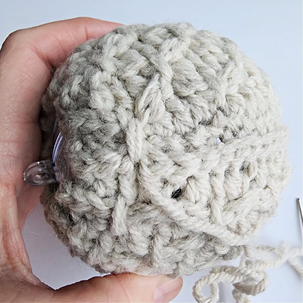 Thread being used to tie the top of the crochet ornament.