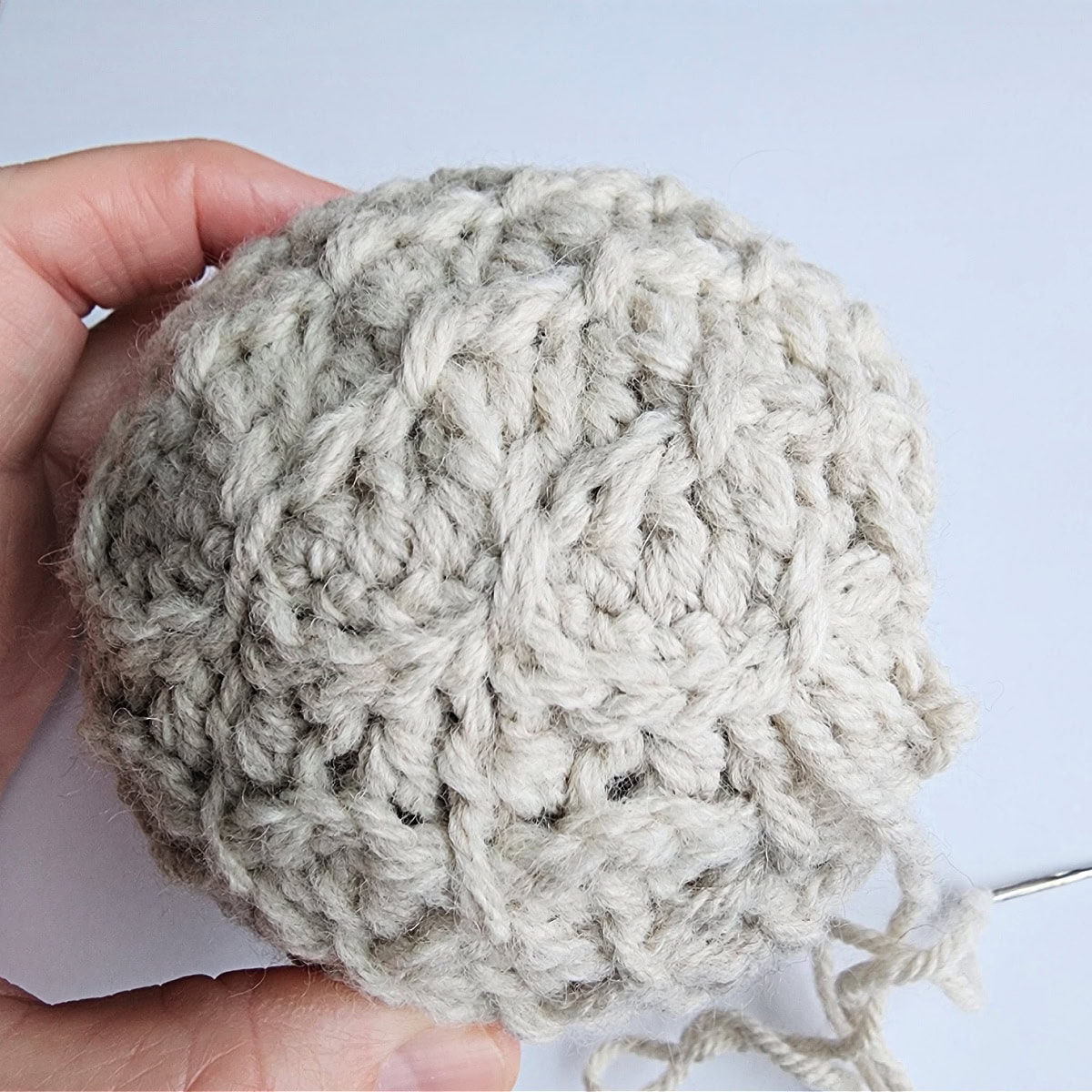Thread being used to tie the top of the crochet ornament.
