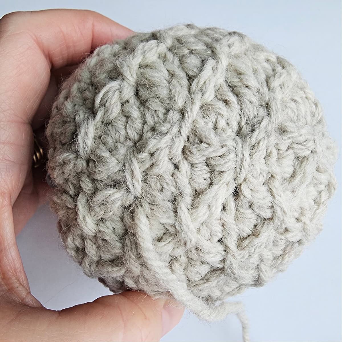 Thread being used to tie the top of the crochet ornament.