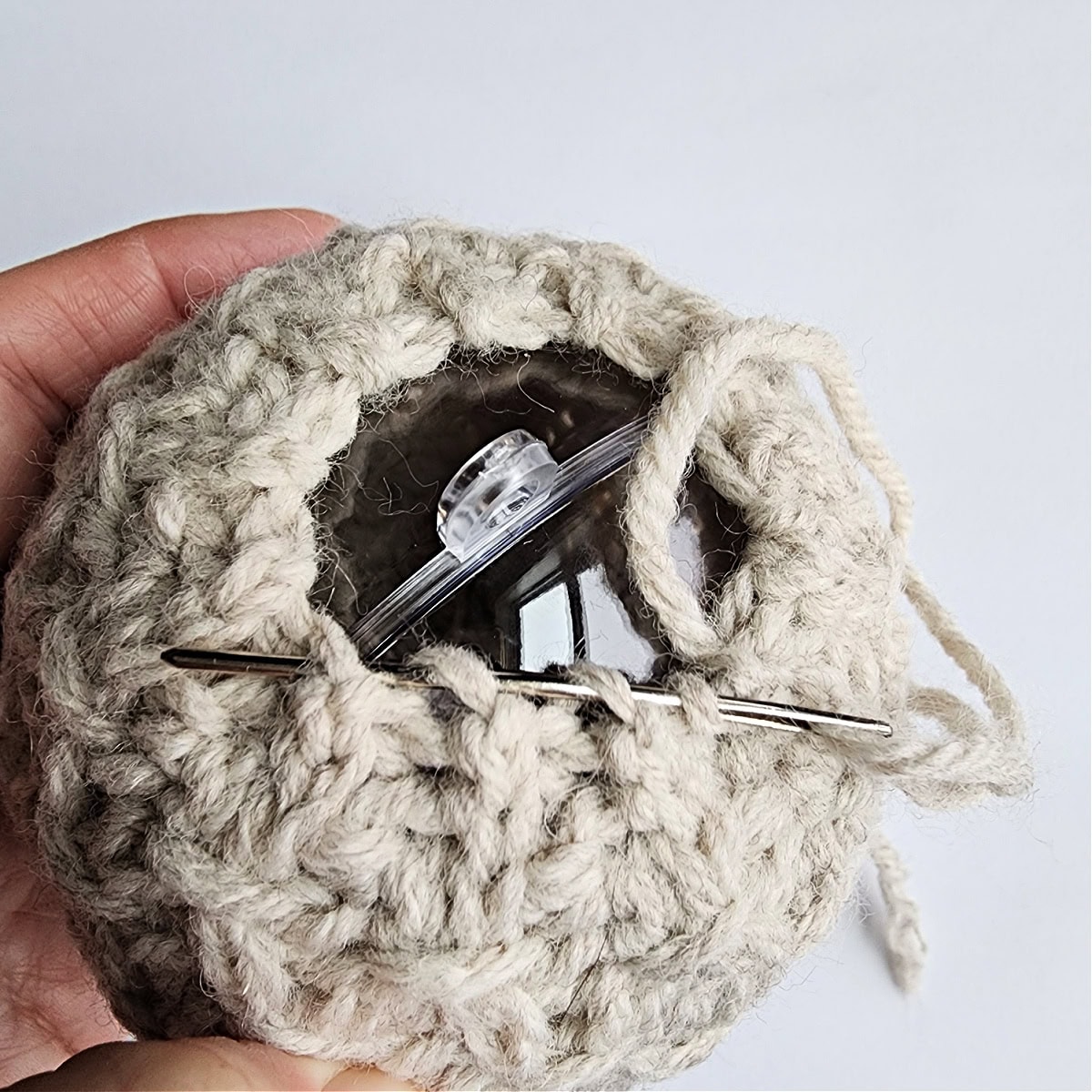 The top of a handmade crochet ornament with a needle.