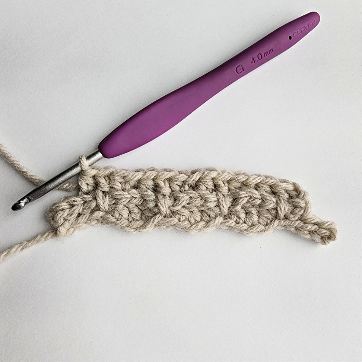 Row 3 of the crochet ornament with a purple crochet hook.