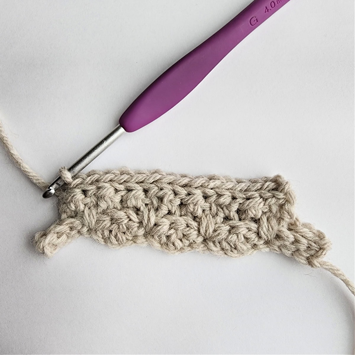 Row 4 of the crochet ornament with a purple crochet hook.