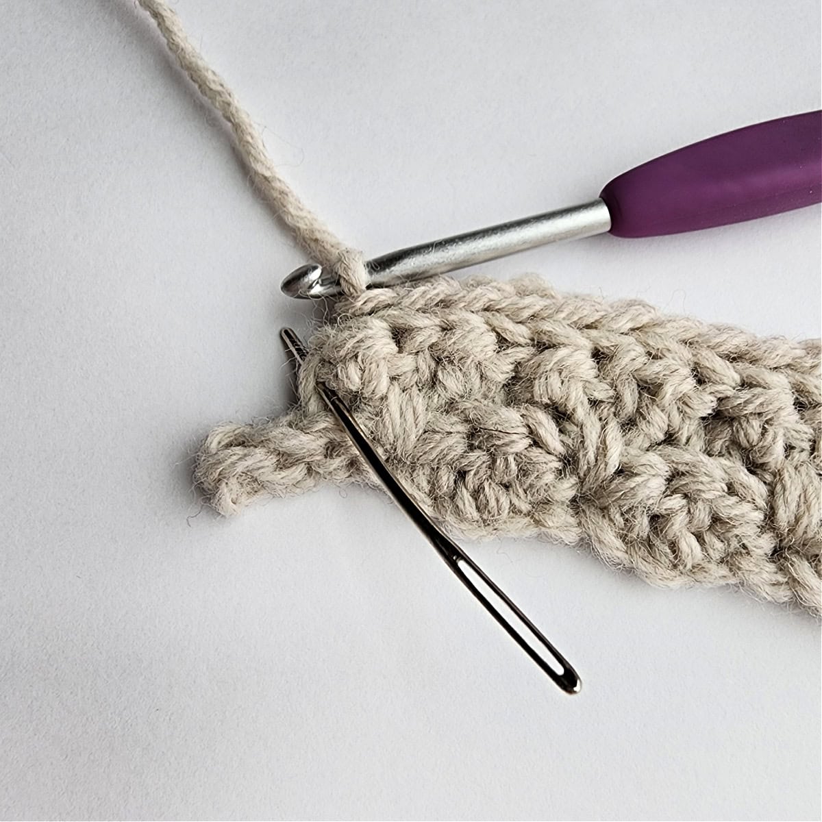 Row 4 of the crochet ornament with a purple crochet hook.